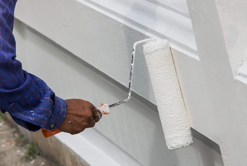 Close up of painter hand in white glove painting a wall with paint roller